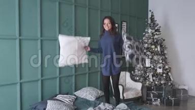 女人在圣诞树旁的床上<strong>蹦蹦</strong>跳跳。节日早晨美丽的旅馆房间